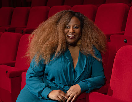 Portrait of Maya Cade sitting in a theater.